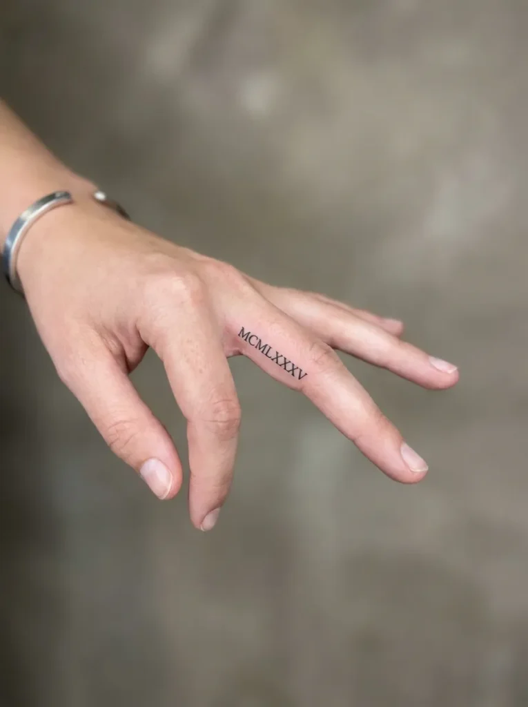 Tiny Roman Numeral Inner Finger Tattoo